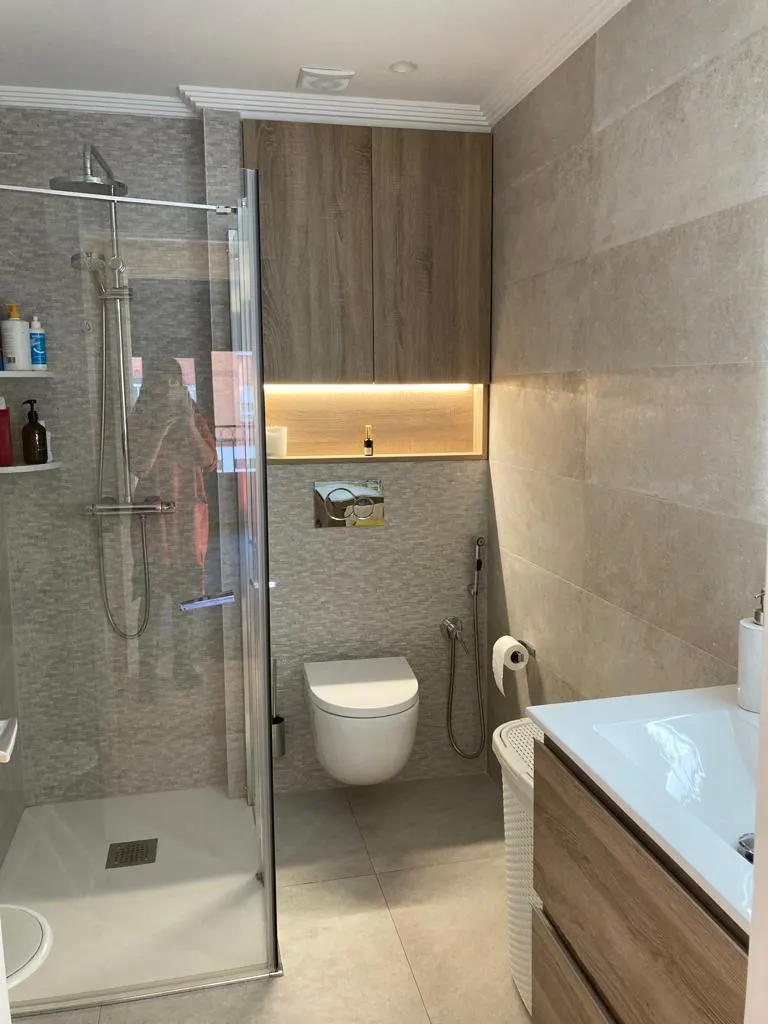 Cuarto de baño con plato de ducha, inodoro y mueble de lavabo.