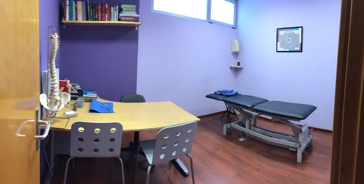 Sala de consulta de Consulta Gihar con mesa de atención y camilla de fisioterapia.