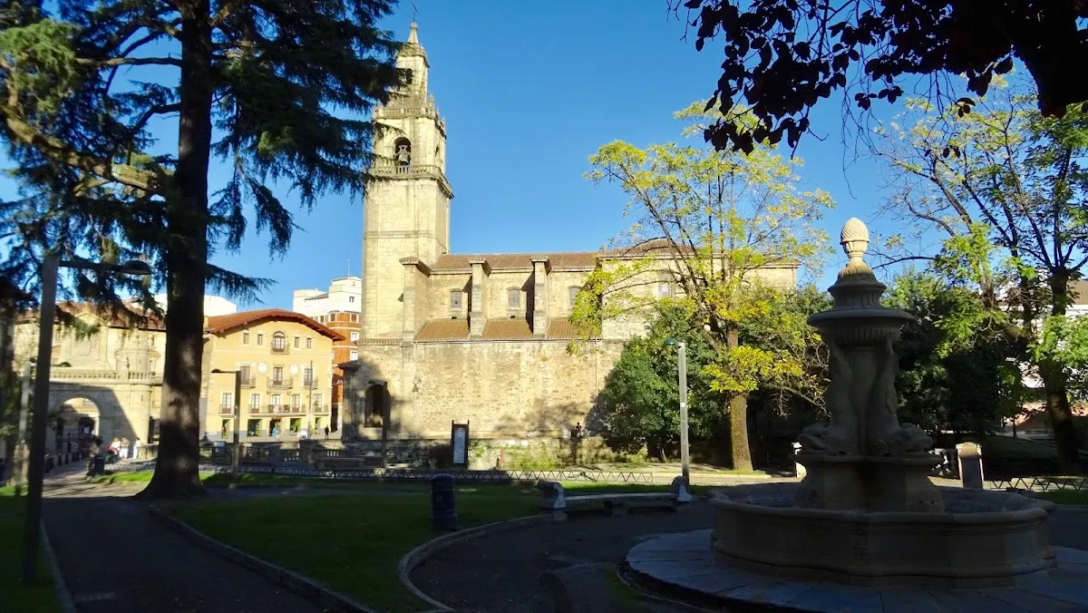 Jardín con fuente y una iglesia al fondo, en un entorno urbano.