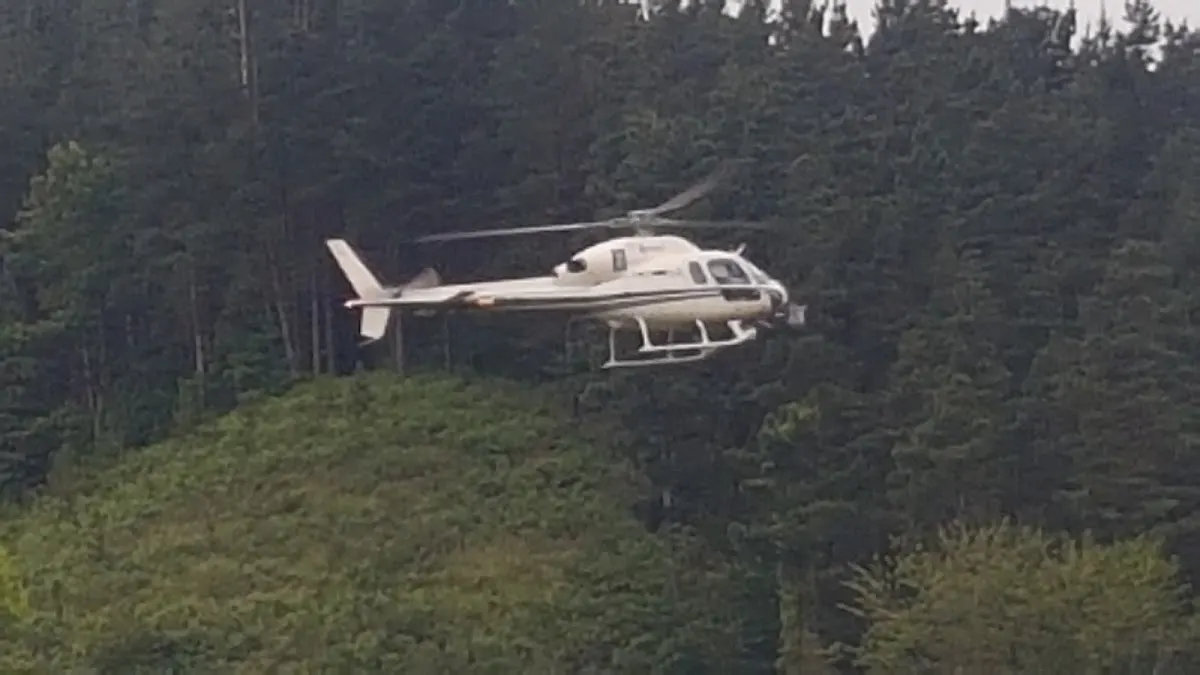 Helicóptero sobre una zona boscosa cercana a las instalaciones