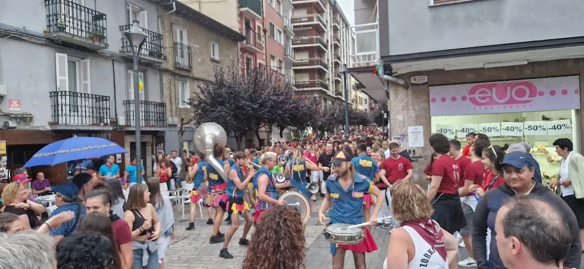Personas y músicos participan en un acto en una calle de Durango, frente a varios comercios.