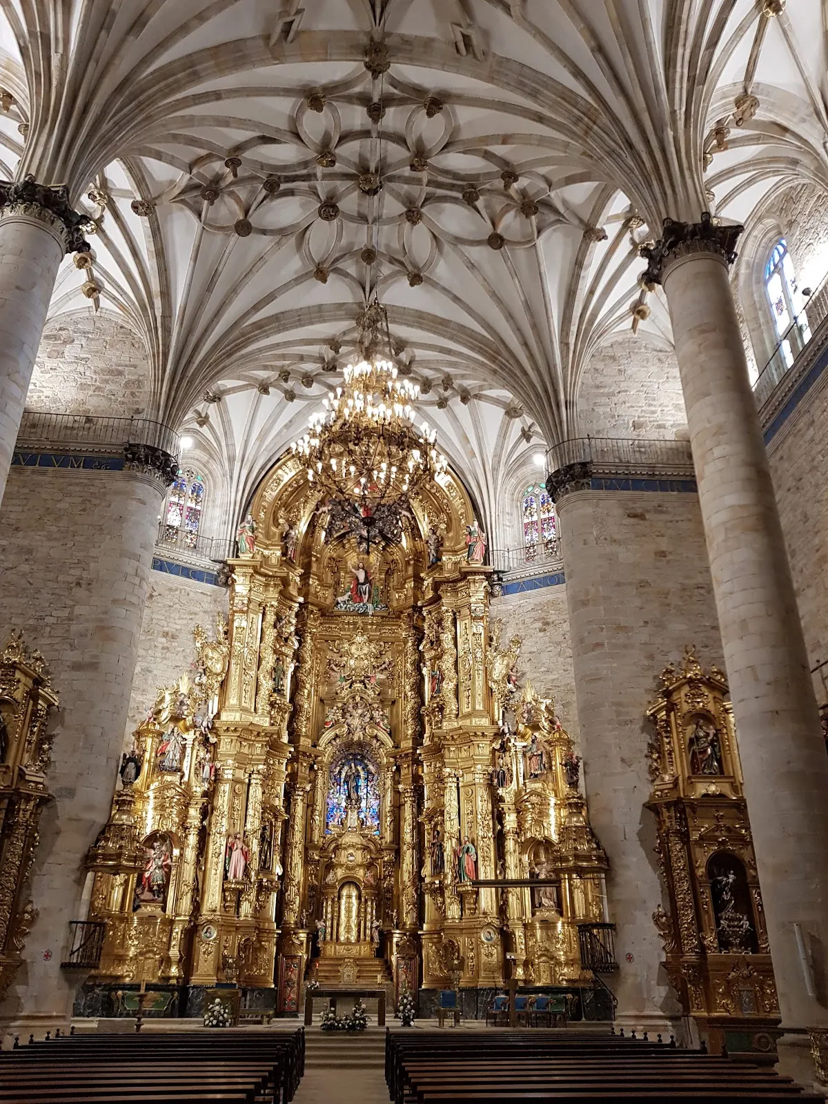 Retablo dorado en el interior de una iglesia con bóveda de crucería