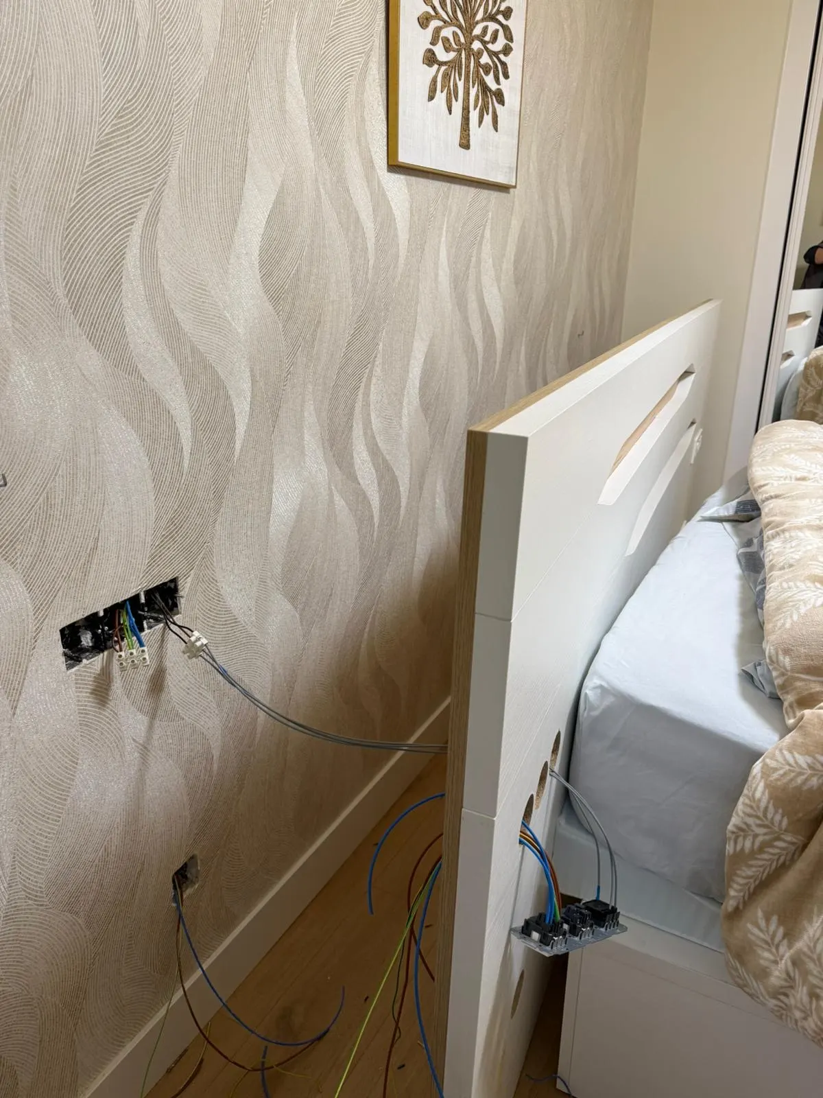 Cableado eléctrico junto a una cama durante una instalación en una vivienda