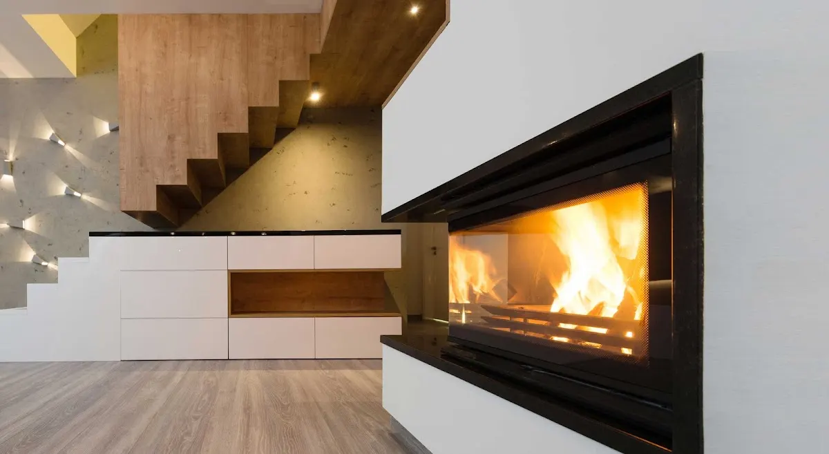 Chimenea insertable encendida bajo una escalera de madera.
