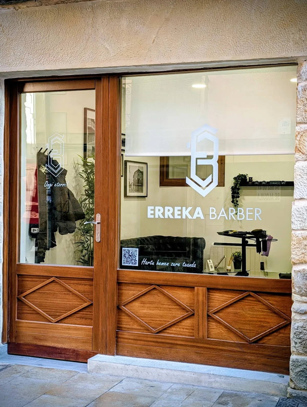 Fachada de ERREKABARBER, barbería con carpintería de madera y rótulo en el escaparate.