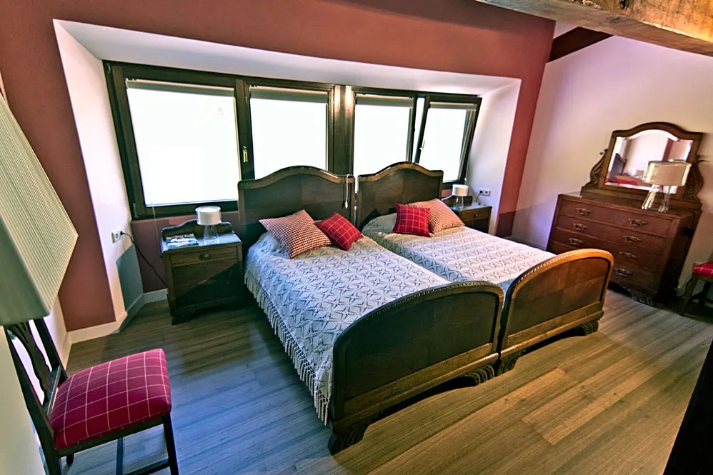 Dormitorio de Esteñibar Baserria con dos camas juntas y mobiliario de madera.