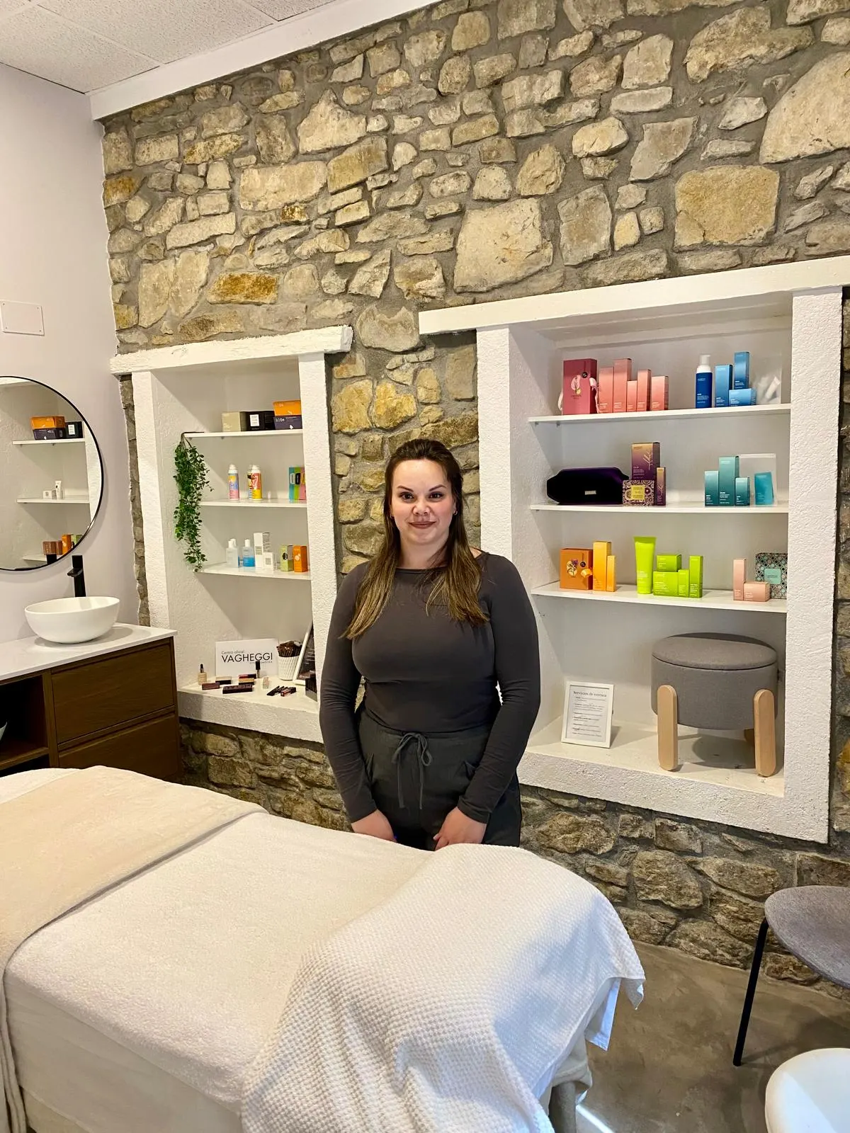 Esteticista en el interior de Estética J.G.M., junto a la camilla y estantes de productos.
