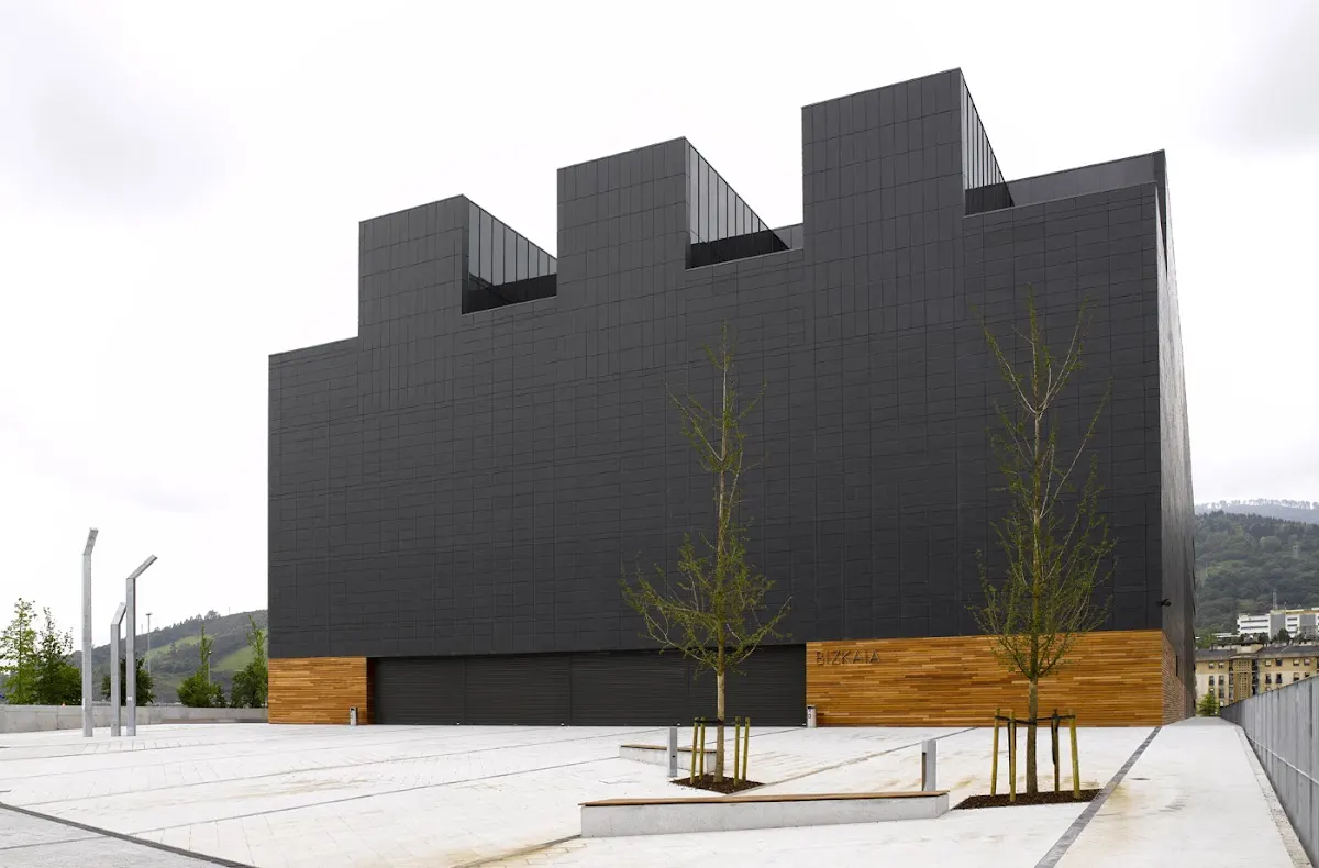 Edificio de fachada oscura y volúmenes escalonados, obra mostrada por URRELAN Arquitectura Técnica