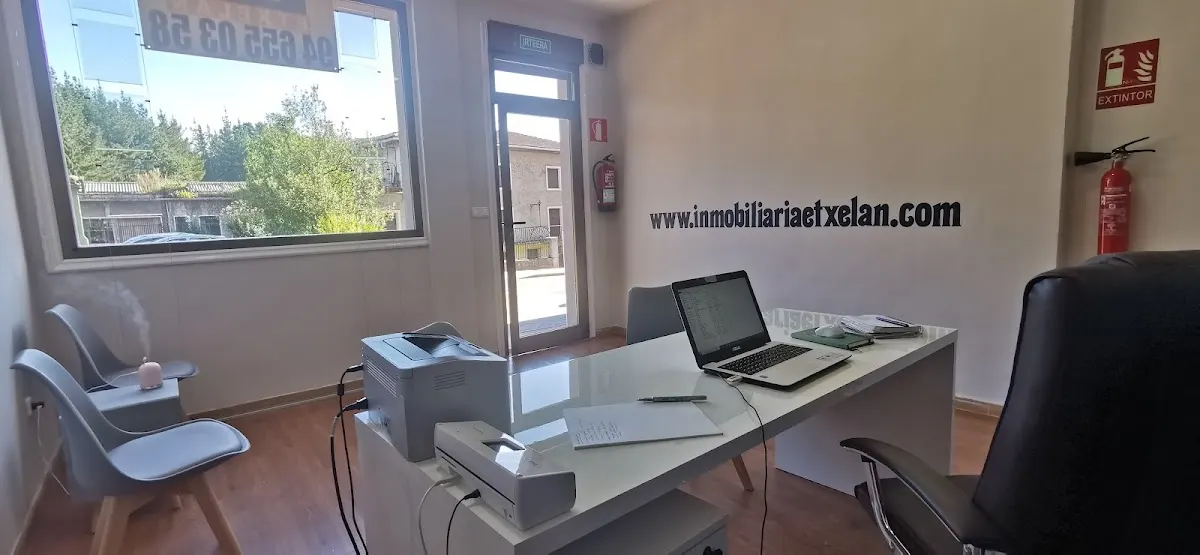 Interior de una oficina de Etxelan Inmobiliaria, con mesa de trabajo y sillas de espera.