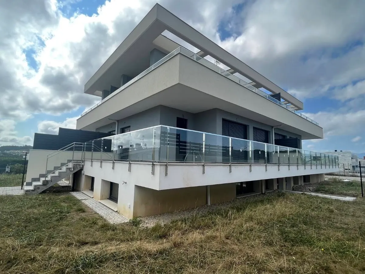 Edificio moderno de varias plantas con balcones y barandillas de vidrio.