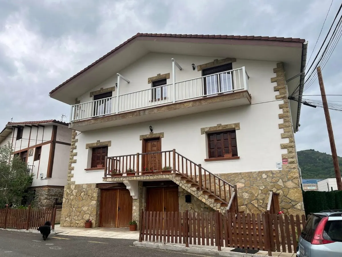 Vivienda de dos plantas con escalera exterior y barandillas metálicas.