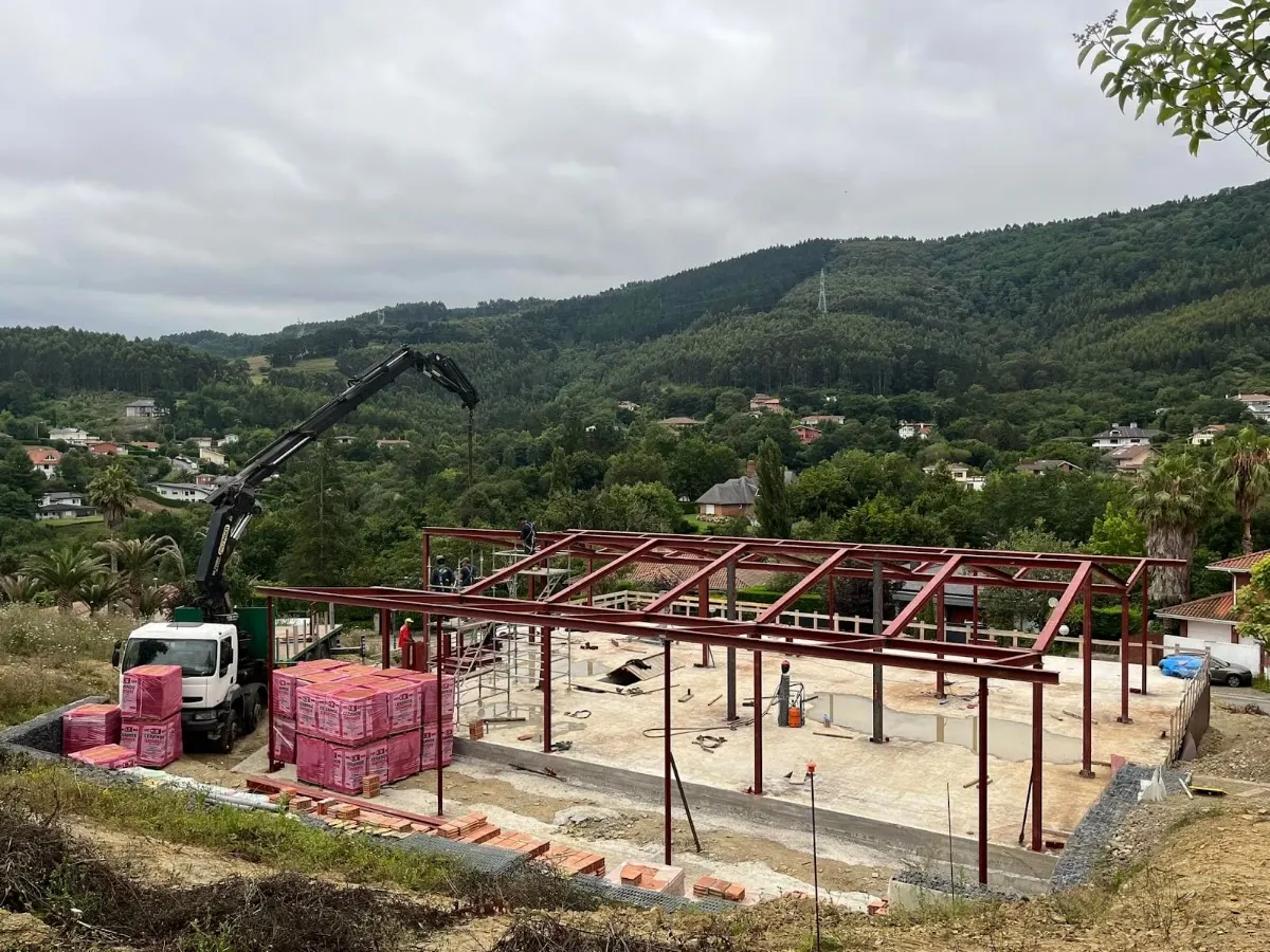 Estructura metálica en montaje en una obra, junto a un camión grúa.