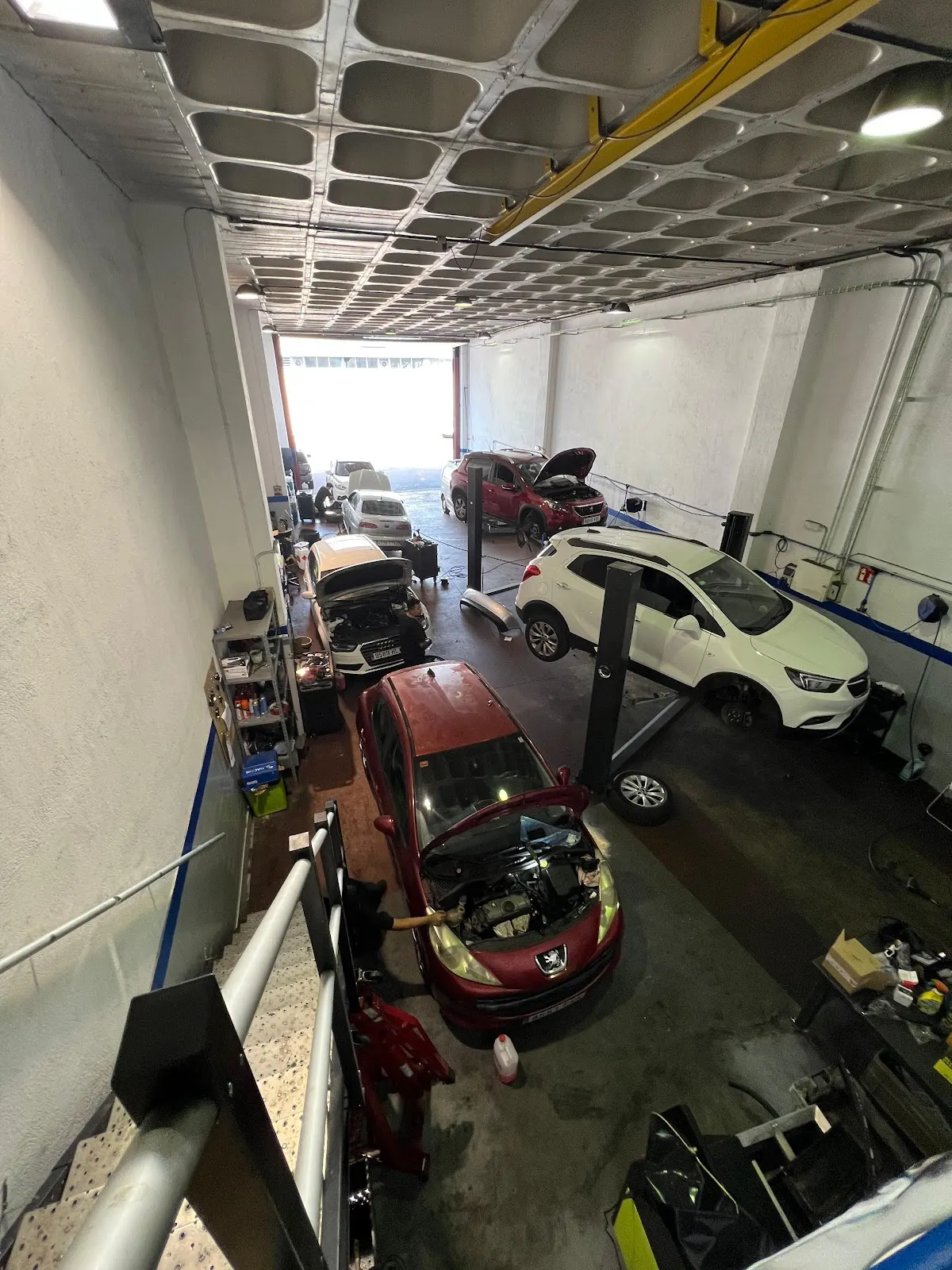Interior del taller de F&F Soluciones Electromecánicas S.L. con varios coches en reparación.