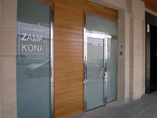 Entrada de Fisioterapia Maria Zamakona en Durango, con el nombre del centro en el cristal.