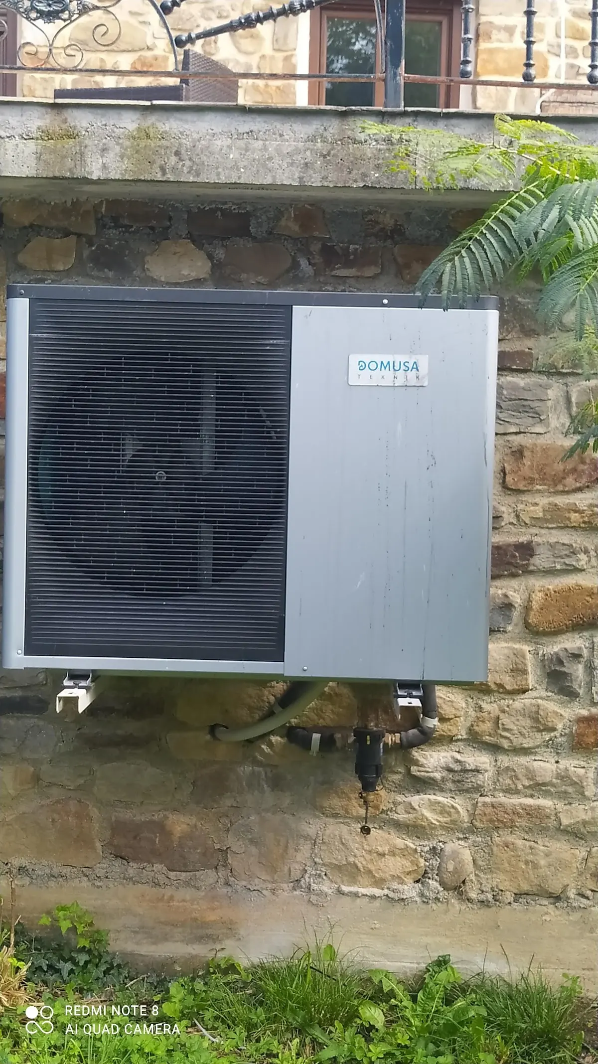 Unidad exterior de climatización instalada en una pared de piedra, en una imagen de Fontanería DUAM SL.