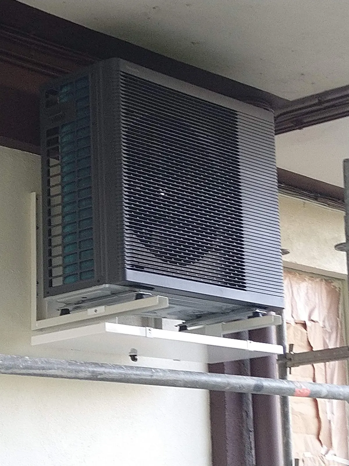 Unidad exterior de climatización colocada en un soporte alto, en una imagen de Fontanería DUAM SL.