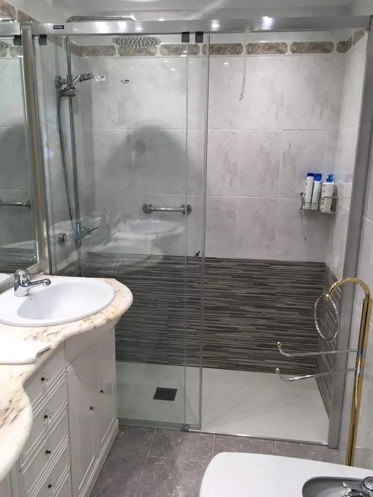 Baño reformado con ducha de mampara, lavabo y azulejos