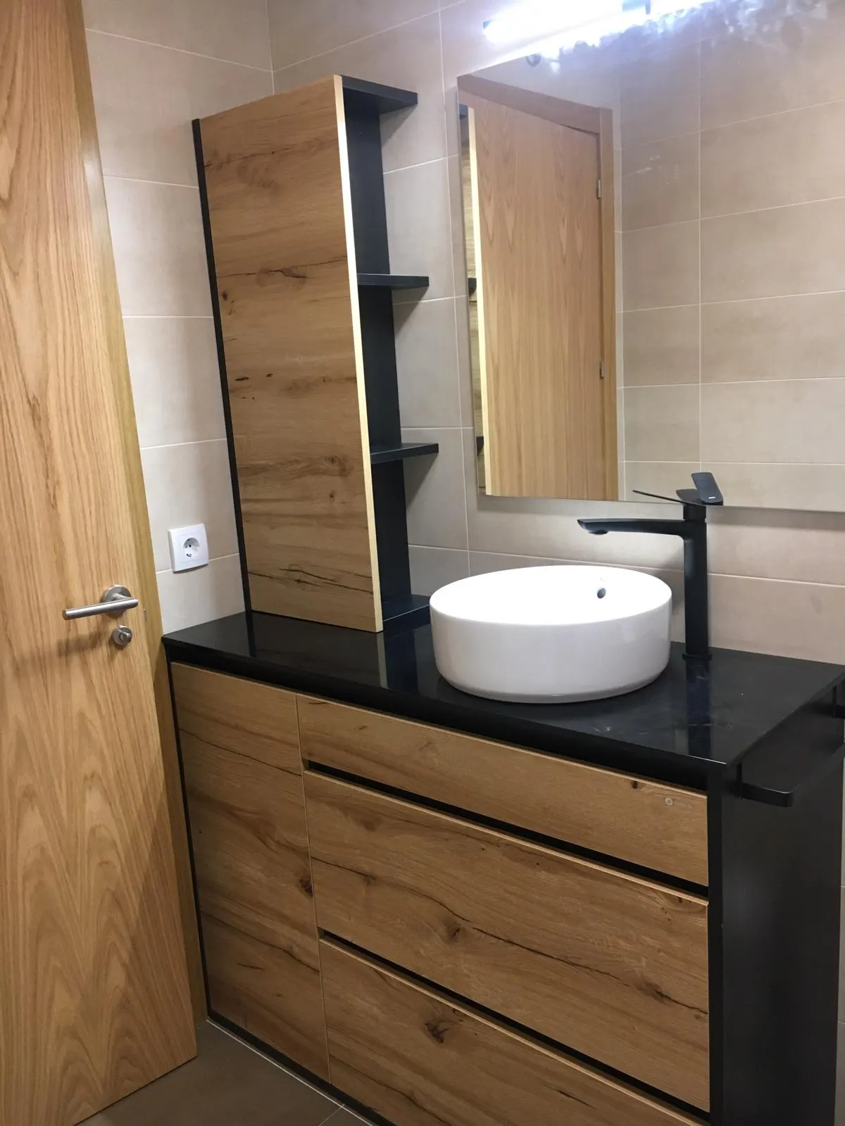 Mueble de lavabo de madera y encimera oscura en un baño