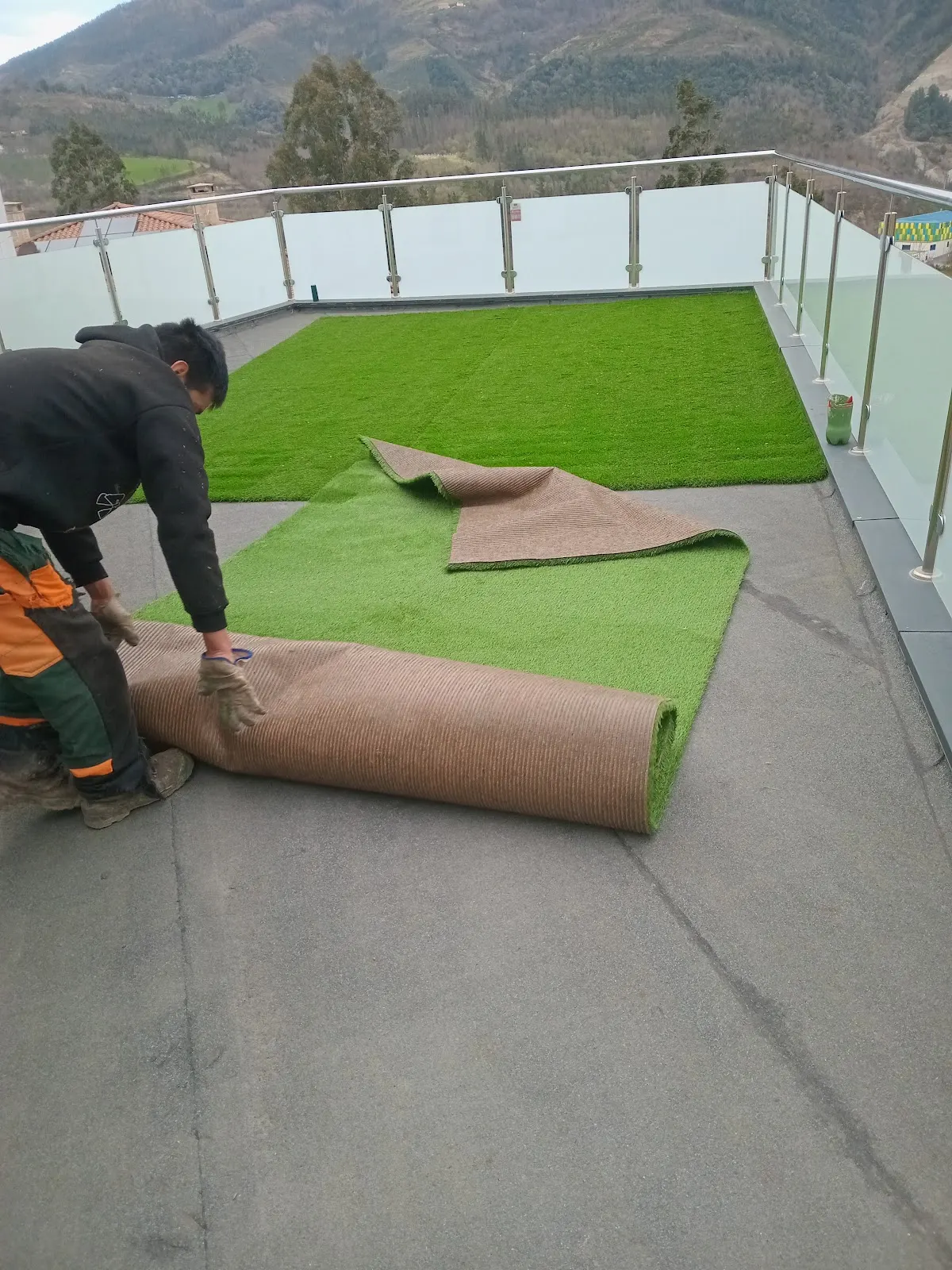 Un trabajador extiende césped artificial en una terraza, en una imagen de Forestales y Jardinería Loois.