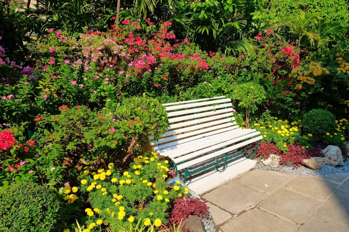 Banco rodeado de flores y plantas en un jardín.