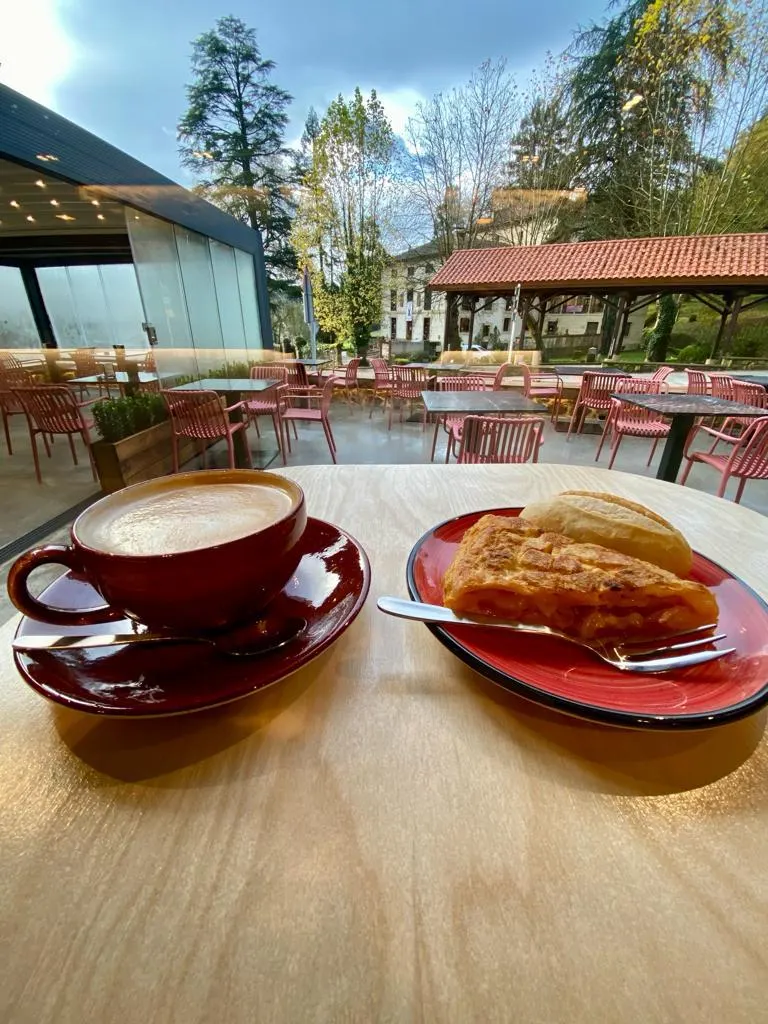Café y porción de tortilla servidos en una mesa de la terraza de Ganeko Learreta markina.