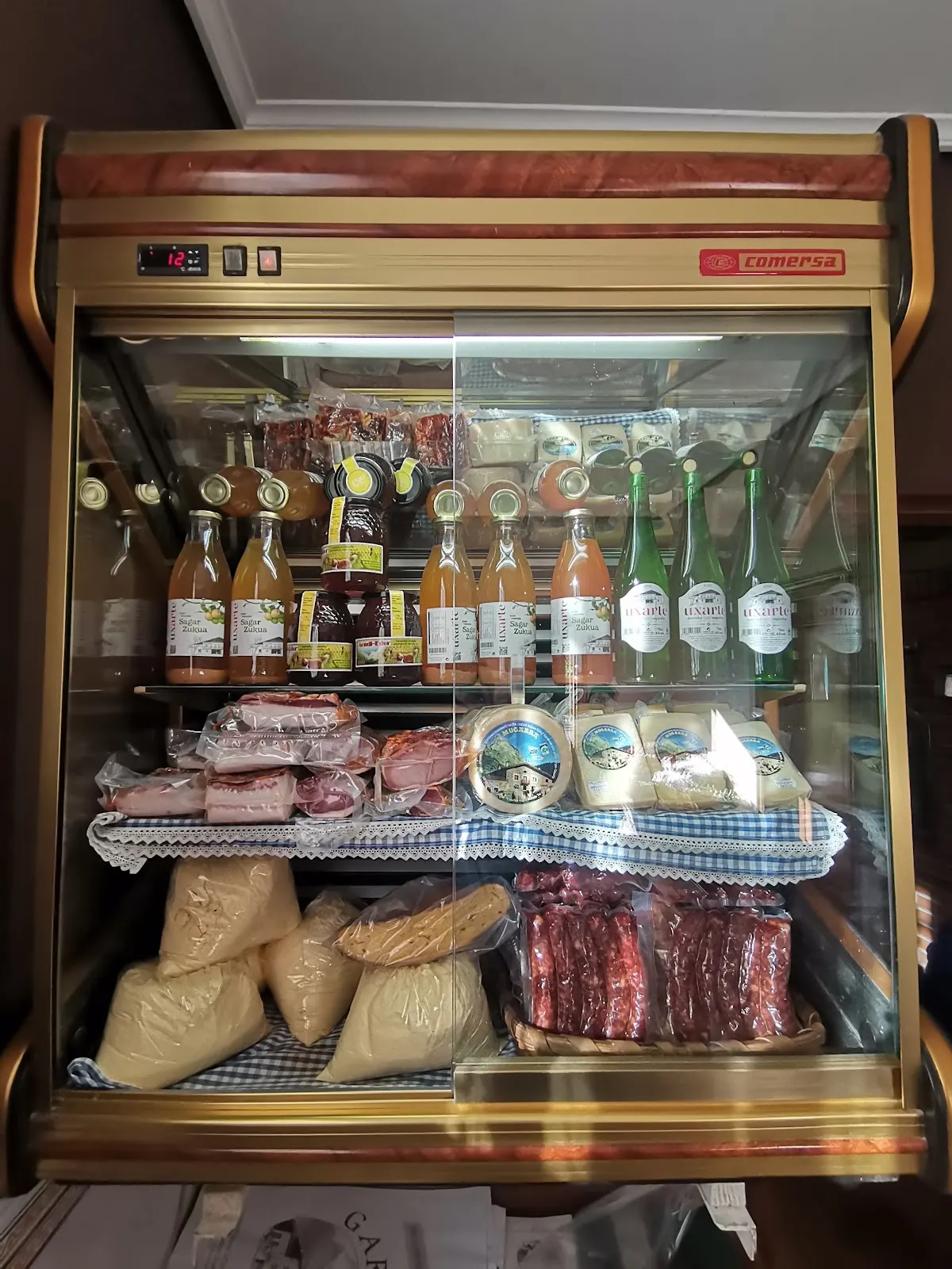 Expositor refrigerado de Garate Baserriko Ogia con bebidas, quesos y embutidos.