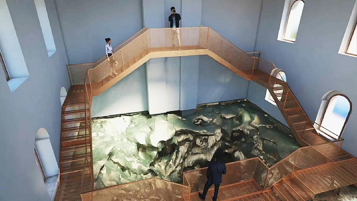 Vista de una instalación interior con una estructura elevada alrededor de un espacio con rocas.