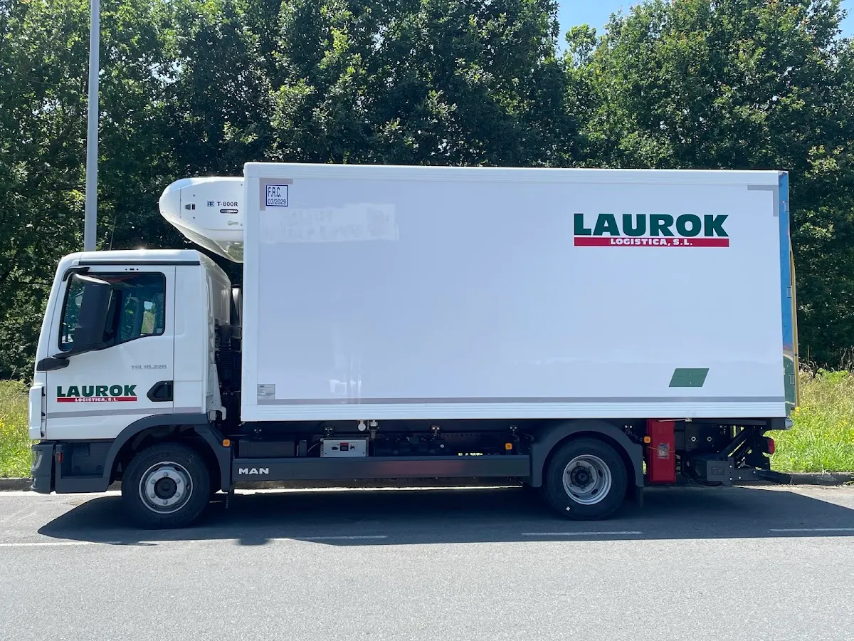 Camión frigorífico de Grupo Lan Logística estacionado junto a una zona arbolada.