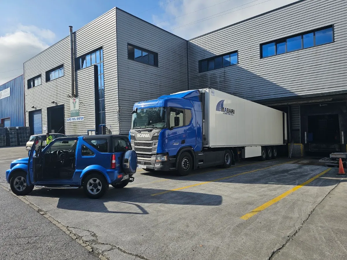 Camión de transporte frente a una nave industrial.