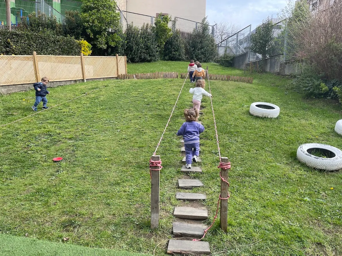 Niños recorren un circuito de equilibrio en el jardín de Haurreskola Karmeltxo.