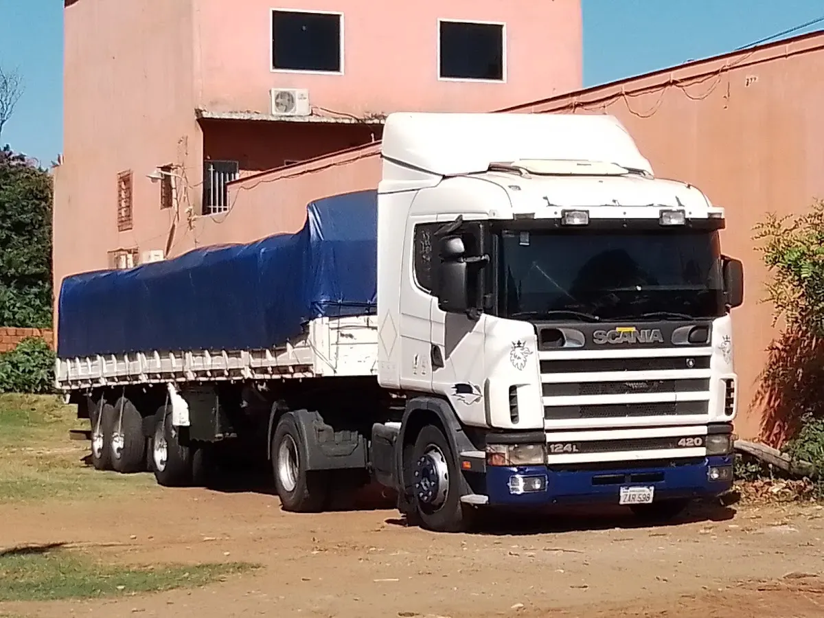 Camión de transporte con lona azul frente a un edificio industrial