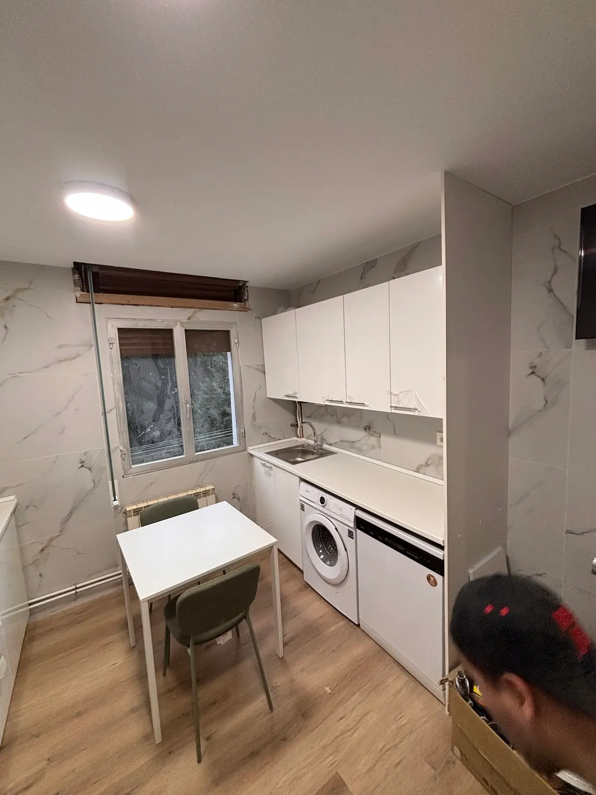 Cocina reformada con muebles blancos, zona de lavado y mesa de comedor.