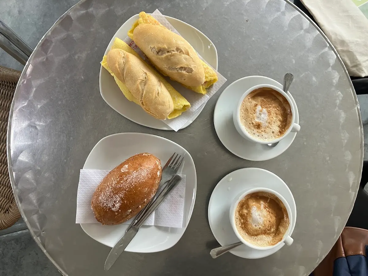 Café, bocadillos y bollo servidos en una mesa de Herria Taberna.