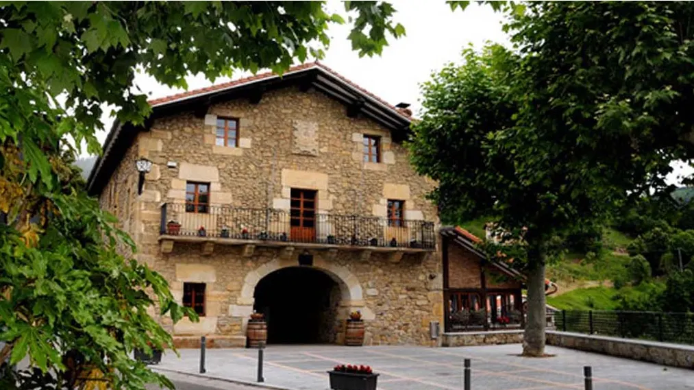 Fachada de piedra de Herriko Jatetxea Garai entre árboles