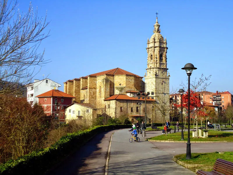Vista de una iglesia con torre y edificios en un parque urbano