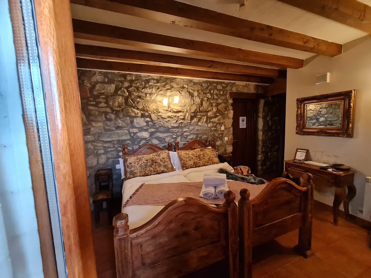 Habitación del Hotel Rural Mañe con cama de madera y paredes de piedra
