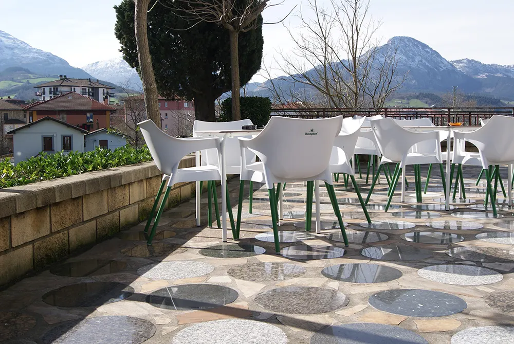 Terraza exterior del Hotel San Blas con mesas, sillas y vistas a las montañas.