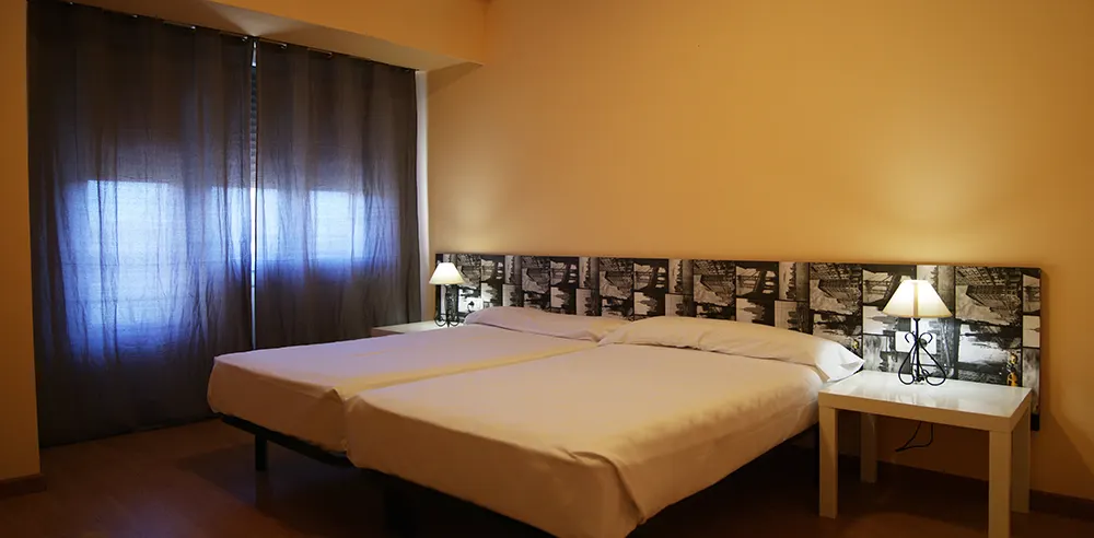 Habitación del Hotel San Blas con dos camas y mesillas.