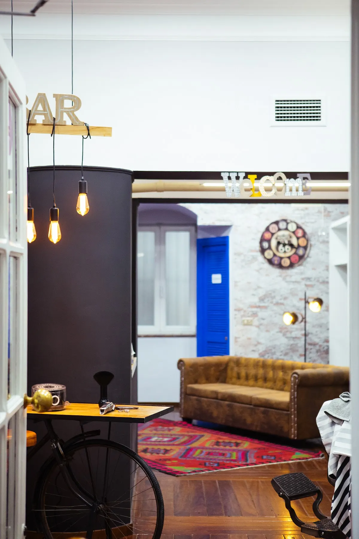 Interior de Ibra,s barber shop con sillón de barbero, sofá y decoración de estilo industrial.