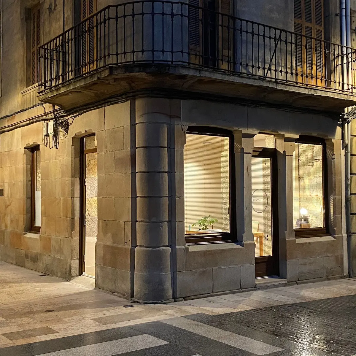 Fachada de un edificio en esquina con balcones y ventanales iluminados por la noche
