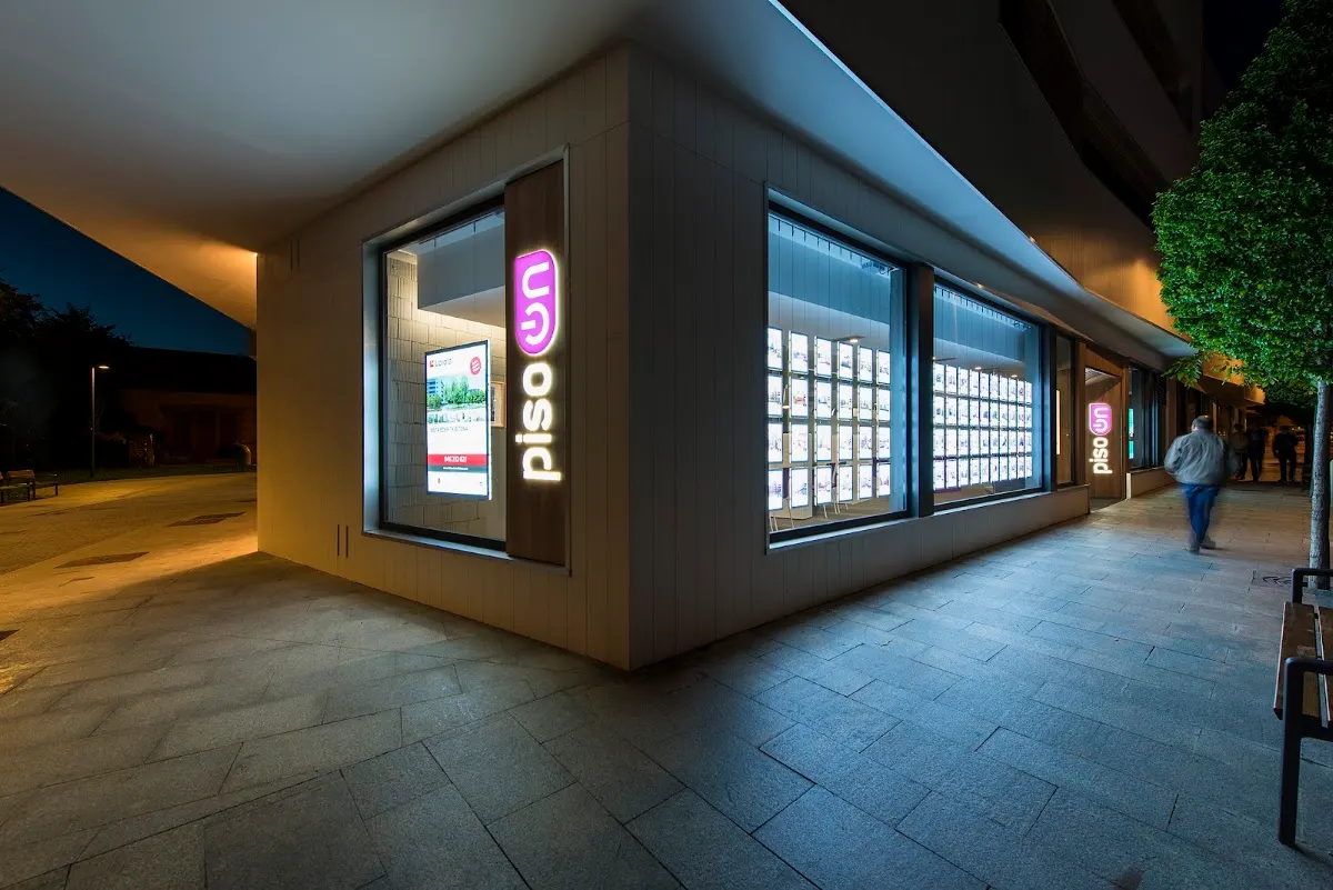 Fachada de Inmobiliaria Piso On Durango iluminada por la noche.