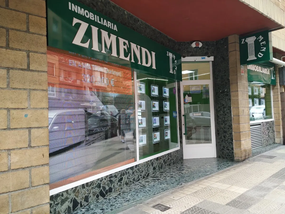 Fachada de Inmobiliaria Zimendi en Durango, con escaparate de anuncios inmobiliarios.