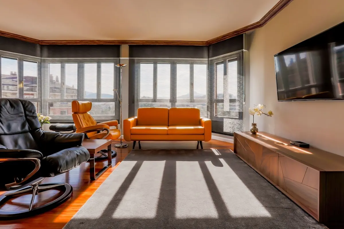Salón con sillones, sofá y ventanales, en una imagen de interiores de Alki