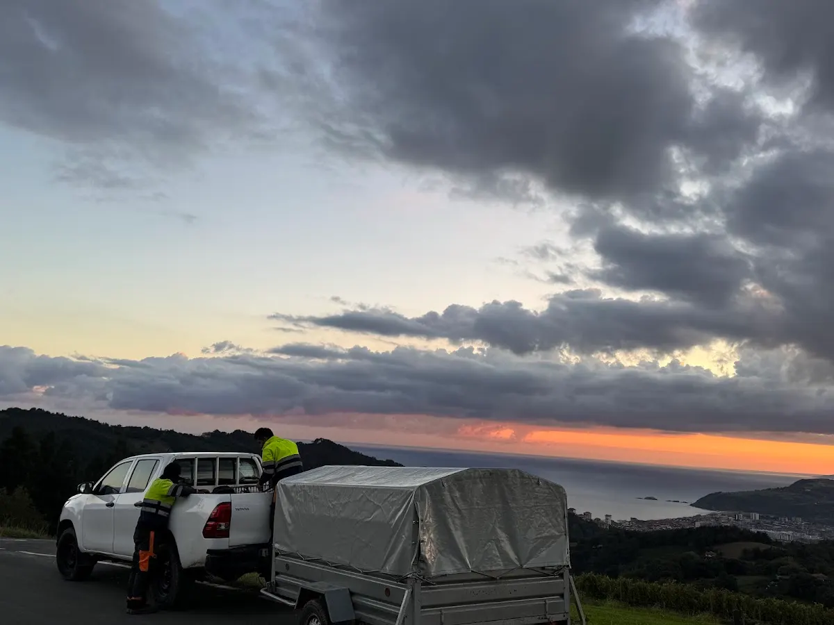Dos trabajadores junto a una camioneta con remolque en un paisaje al atardecer, imagen asociada a Intilur Forestal.