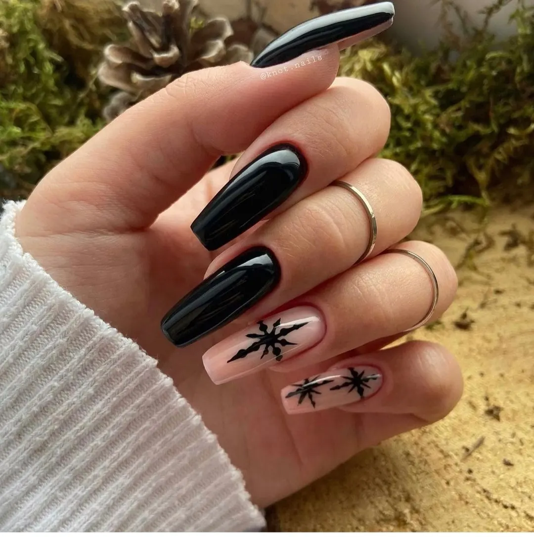 Manicura negra con diseños decorativos en las uñas.