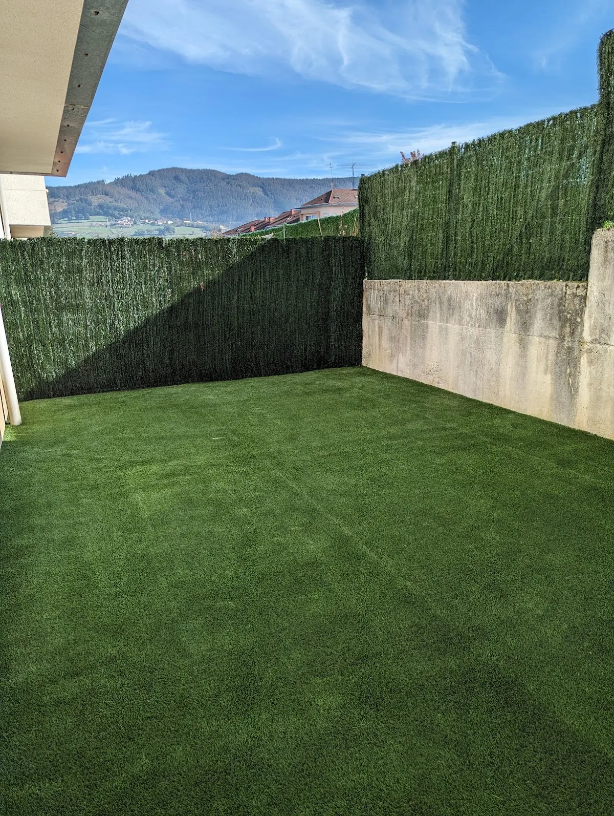 Jardín con césped artificial y cerramiento de ocultación