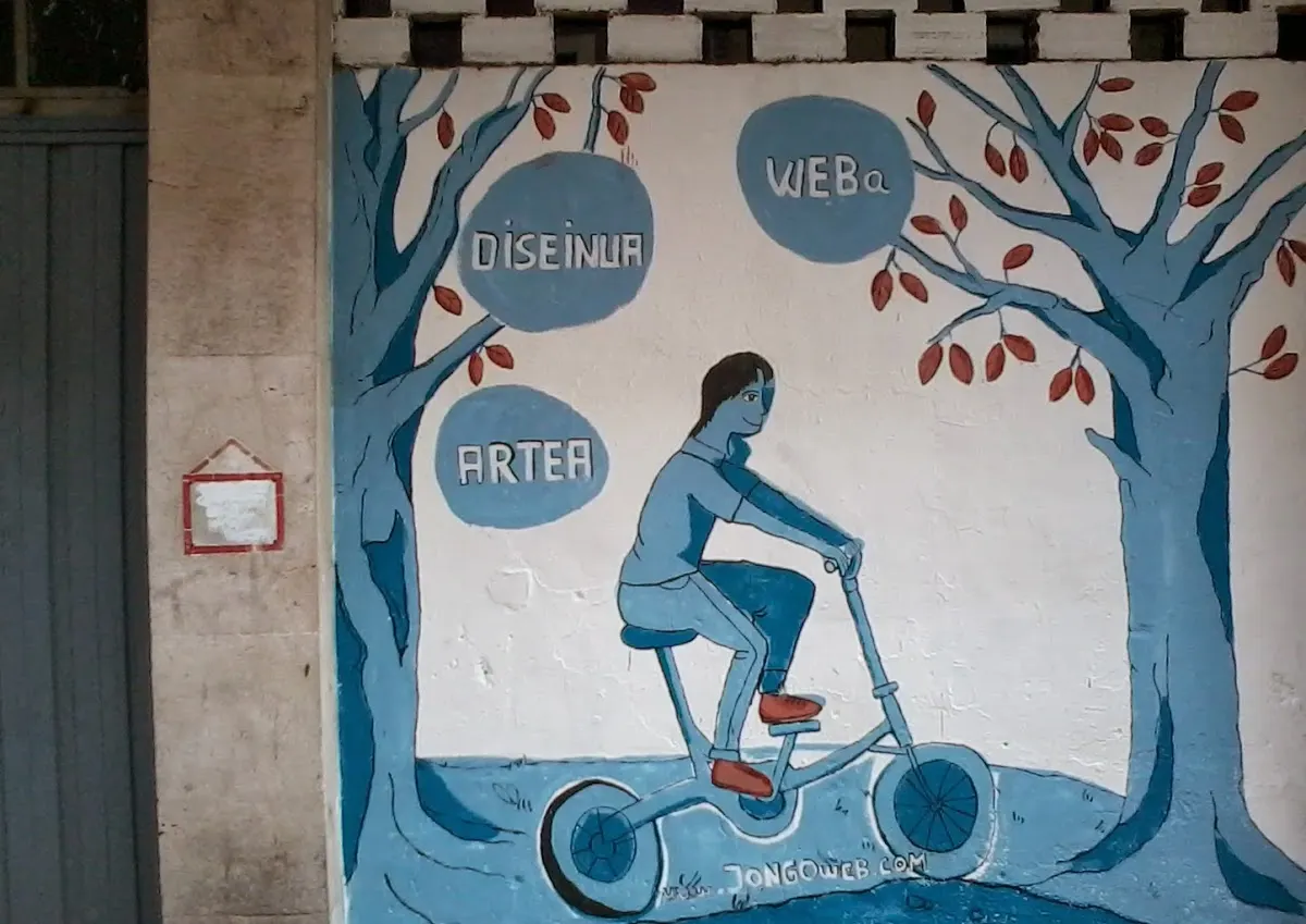 Mural pintado en una pared con una persona en bicicleta y palabras sobre diseño y arte.