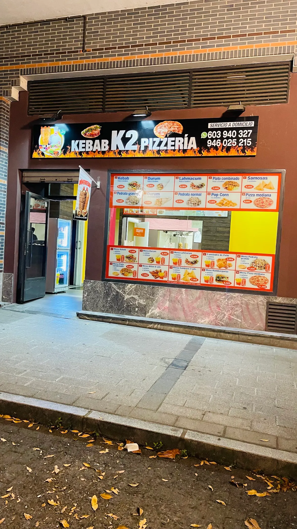 Fachada de K2 Kebab Pizzería en Amorebieta-Etxano, con el rótulo y el menú expuesto en el escaparate.