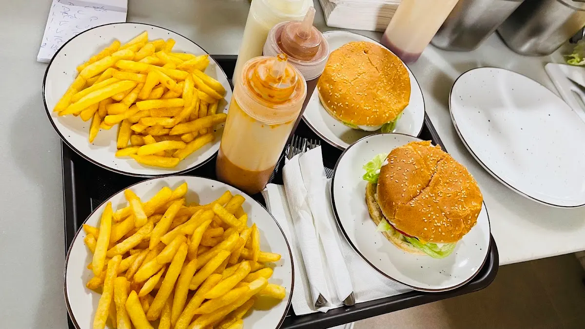 Bandeja con patatas fritas, hamburguesas y salsas de K2 Kebab Pizzería.
