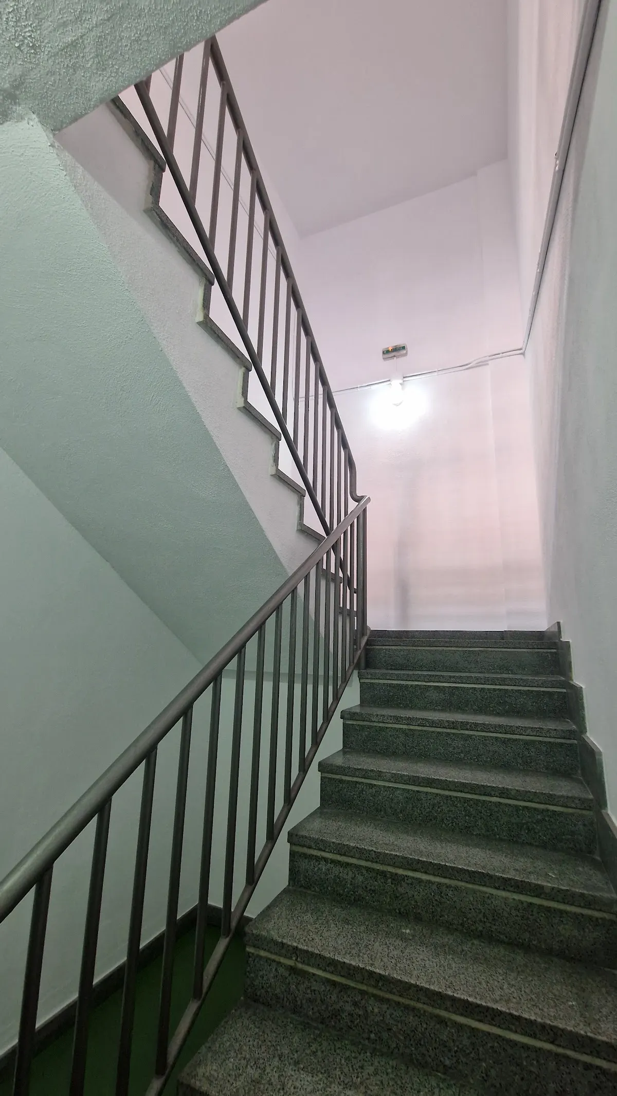 Escalera comunitaria con paredes claras y barandilla metálica, en una imagen de Kadi Pintores